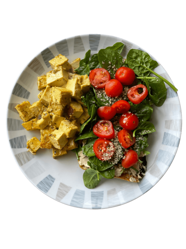 A plate of tofu scramble with spinach and cherry tomatoes